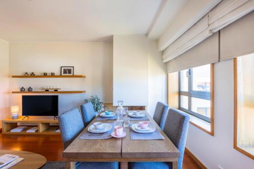 a dining room with a wooden table and blue chairs at Foz Premium Retreat in Porto