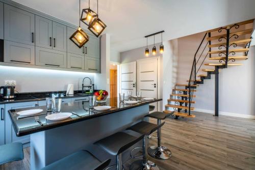 a kitchen with a bar with stools and a staircase at Apartamenty U Andzi in Białka Tatrzanska