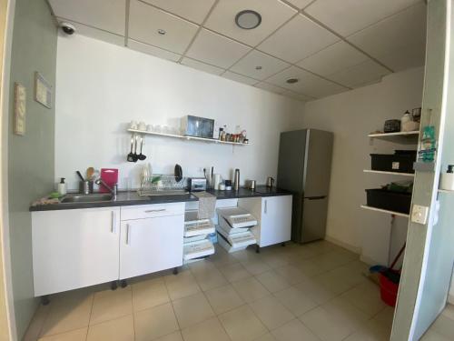 a kitchen with white cabinets and a stainless steel refrigerator at NC Hostel in Las Palmas de Gran Canaria
