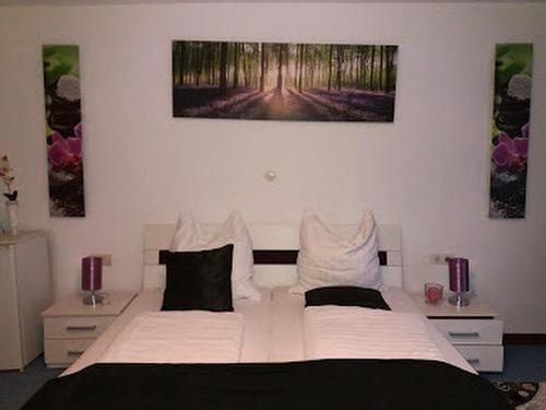 um quarto com uma grande cama branca e duas pinturas na parede em Hotel Restaurant Toscana em Bad Orb