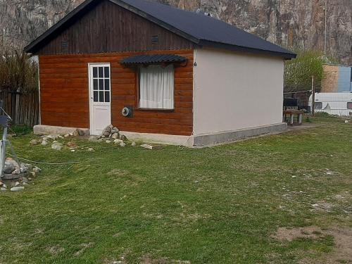 a small cabin with a white door in a yard at Nativos in El Chalten