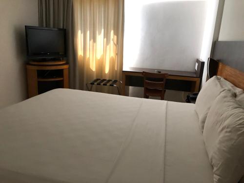 een slaapkamer met een bed en een flatscreen-tv bij FLAT NATAL PLAZA in Natal