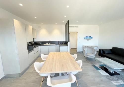 Il dispose d'une cuisine et d'un salon avec une table et des chaises en bois. dans l'établissement Viva Riviera Deluxe Top Floor 2 Bedrooms 2 Bathrooms, à Cannes