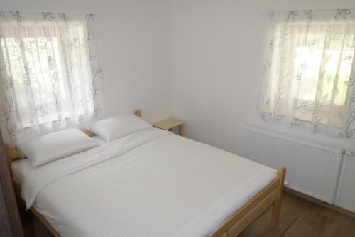a white bed in a room with two windows at Hiša Lenart in Tolmin