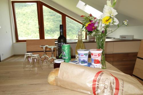 a table with a paper bag and bottles of wine and flowers at Hiša Lenart in Tolmin