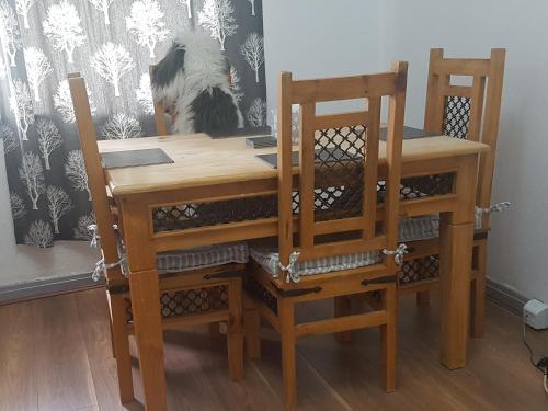 una mesa de madera con 2 sillas y una mesa con papel pintado de perro en Cosy Room in Galashiels, en Galashiels