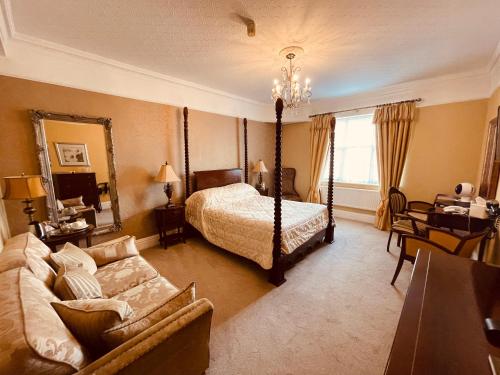 a bedroom with a bed and a couch and a mirror at Nuthurst Grange Country House Hotel & Restaurant in Solihull