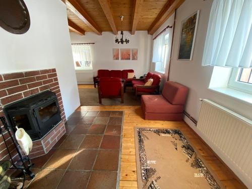 ein Wohnzimmer mit einem Kamin und roten Stühlen in der Unterkunft Chata Maxík in Josefův Důl u Jablonce nad Nisou