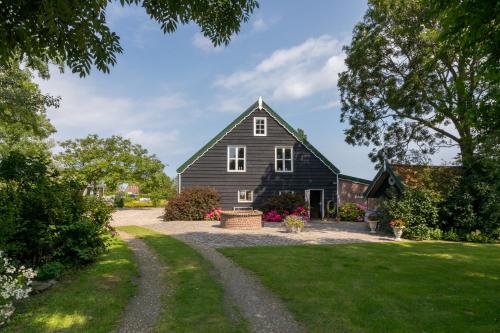 a black barn with a gravel driveway at De Notenboom in Meliskerke