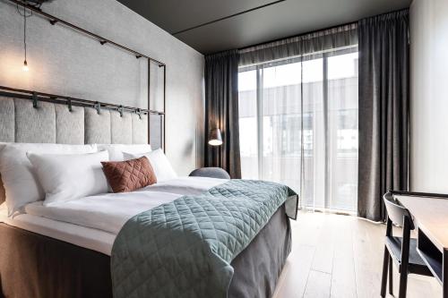 a bedroom with a bed and a desk and a window at Quality Hotel Hasle Linie in Oslo