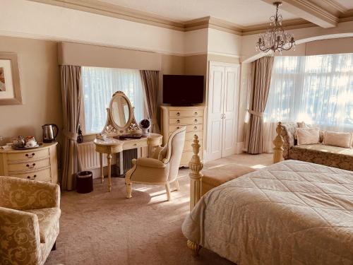 een slaapkamer met een bed, een bureau en een spiegel bij Nuthurst Grange Country House Hotel & Restaurant in Solihull