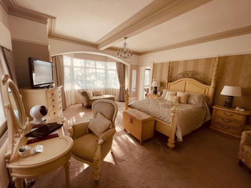 een slaapkamer met een bed, een stoel en een televisie bij Nuthurst Grange Country House Hotel & Restaurant in Solihull