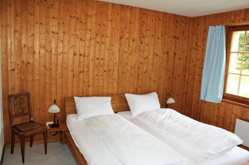 een slaapkamer met een bed met een houten muur bij Chalet Hagenbächli in Schwarzsee