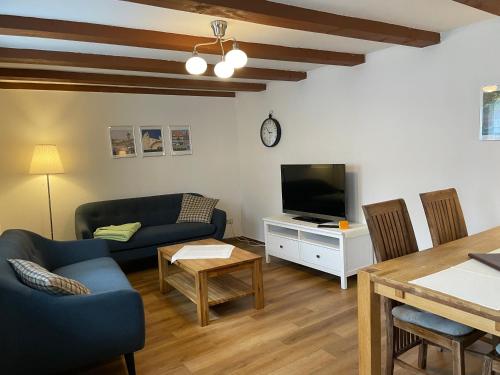 ein Wohnzimmer mit einem Sofa, einem TV und einem Tisch in der Unterkunft Urlaub im Fachwerk - Klink in Quedlinburg
