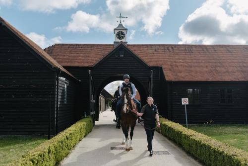 a man riding a horse and a woman walking at Four Seasons Hotel Hampshire in Winchfield