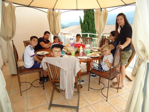 a family sitting at a table with an umbrella at chambres d'hôtes du capimont in Hérépian