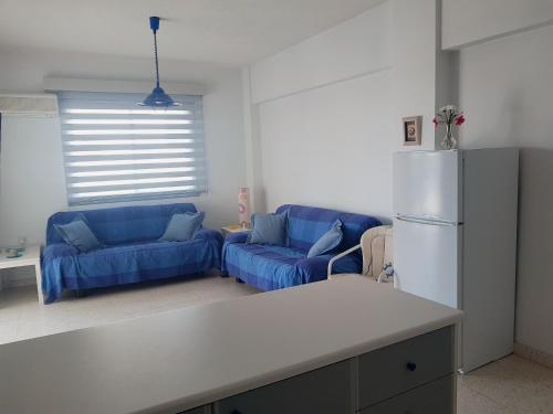 a living room with two blue couches and a refrigerator at Cozy holyday apartament in Paralimni