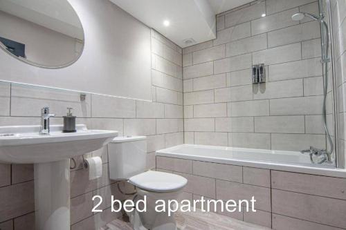 a bathroom with a sink and a toilet and a bath tub at Market Square Grade II Listed Apartment in Macclesfield