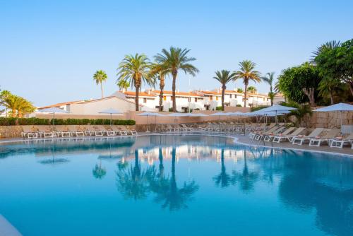 a large swimming pool with chairs and palm trees at Olé Tropical Tenerife Adults Only in Playa de las Americas
