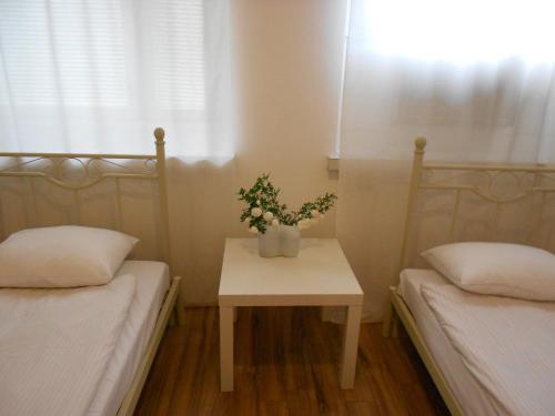 a room with two beds and a table with flowers on it at Anne's City Apartment in Jyväskylä