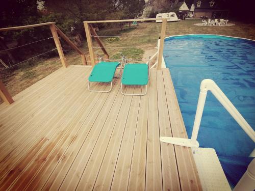 - deux chaises bleues sur une terrasse en bois à côté d'une piscine dans l'établissement le petit secret, à Saint-Hilaire