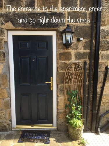 an entrance to a building with a black door and a plant at Otley town centre apartment in Otley