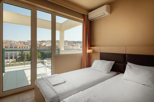 テッサロニキにあるEsperiaのベッド2台と大きな窓が備わるホテルルームです。