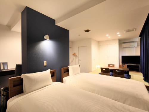 a hotel room with two beds and a television at Hot Spring Inn Hakone Suisen in Hakone