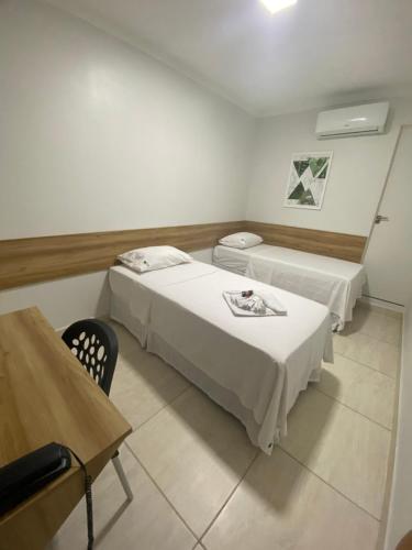 a room with two beds and a table and a desk at Hotel Trevo Caruaru in Caruaru