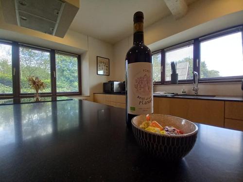 a bottle of wine and a bowl on a table at Le jardin des fagnes in Robertville