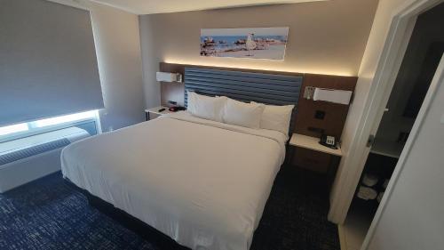 a hotel room with a large bed with white sheets at Wingate by Wyndham Panama City Area Lynn Haven in Panama City