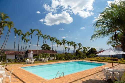 a pool at a resort with palm trees at VOA Mirante Do Café in Santo Antônio do Leite