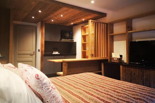 a bedroom with a bed and a tv and a kitchen at Alliey & Spa Piscine Appart-hôtel Serre chevalier in Le Monêtier-les-Bains