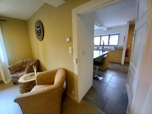 a living room with a couch and a table and a kitchen at Le jardin des fagnes in Robertville