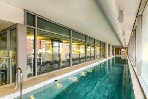 a large swimming pool with blue water in a building at 2-Bed Greenwich Flat + Pool, Gym, Lift, Balcony in London