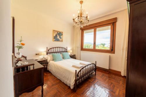 1 dormitorio con cama, ventana y lámpara de araña en Lar de Carmen en Redondela