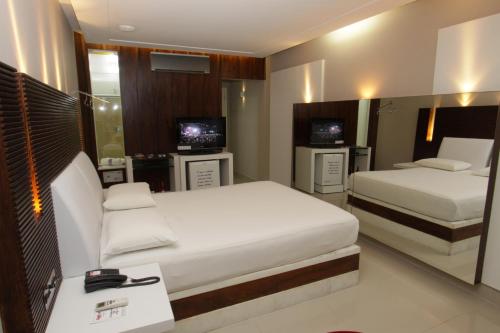 a hotel room with two beds and two televisions at Raru's Motel Cidade Jardim (Adult Only) in Natal