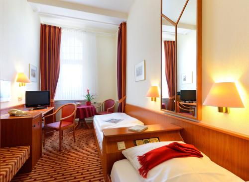a hotel room with two beds and a desk and a mirror at Hotel Schöneberg in Berlin
