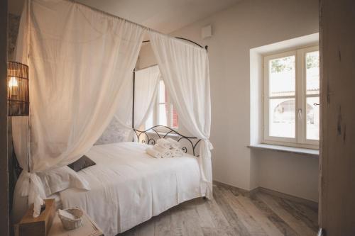 a bedroom with a white bed with a canopy at Relais Almaranto in Calamandrana