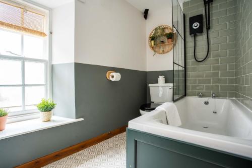 uma casa de banho com uma banheira, um WC e uma janela. em The Bottles Lodge em Alnwick