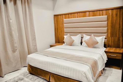 a bedroom with a large bed with a wooden headboard at Doolv Hotel in Hail