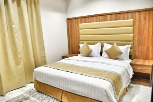 a bedroom with a large bed with a wooden headboard at Doolv Hotel Apartments in Hail
