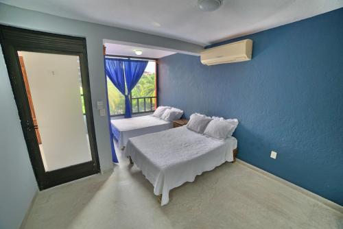 a blue room with two beds and a window at Zihua Mia Hotel Boutique in Zihuatanejo