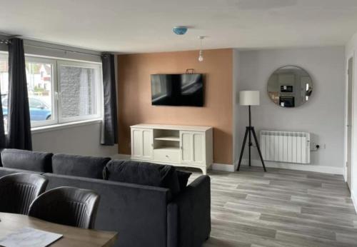 uma sala de estar com um sofá e uma televisão de ecrã plano em Lochaber Apartments em Fort William