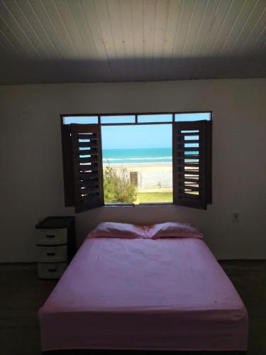 a bedroom with a bed with a view of the ocean at Casa de Praia no Morro Branco in Beberibe