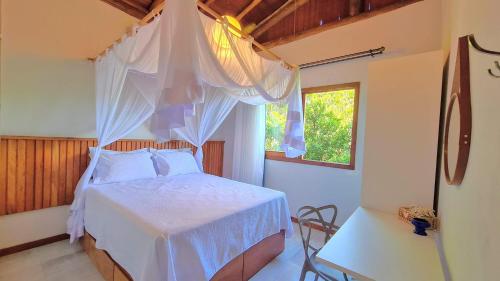 a bedroom with a white bed with a mosquito net at Taipu de Fora - Casa Charme in Barra Grande