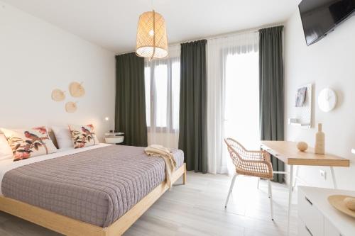 a white bedroom with a bed and a desk and a table at Effie's cozy old town studios in Rethymno Town