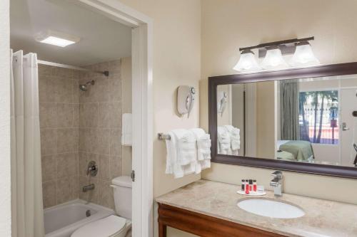 a bathroom with a sink and a toilet and a mirror at Days Inn by Wyndham St. Petersburg / Tampa Bay Area in St Petersburg