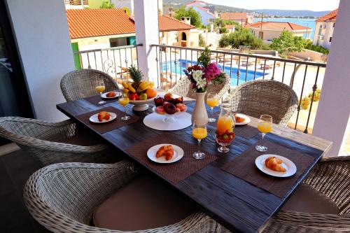 a wooden table with food and drinks on a balcony at Restful Kanica House in Rogoznica