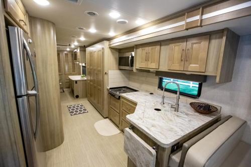an rv kitchen with a sink and a refrigerator at River Safaris New Class A Motorcoach Homosassa with River Accessibility in Homosassa